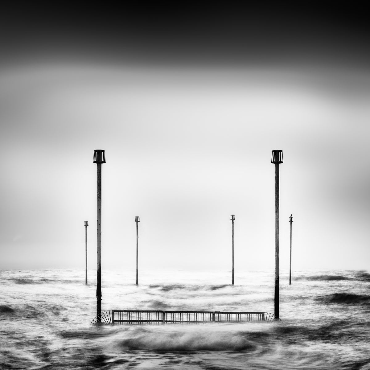 The Hold, two prominent posts and a low railing surrounded by moving water at Shoreham.
