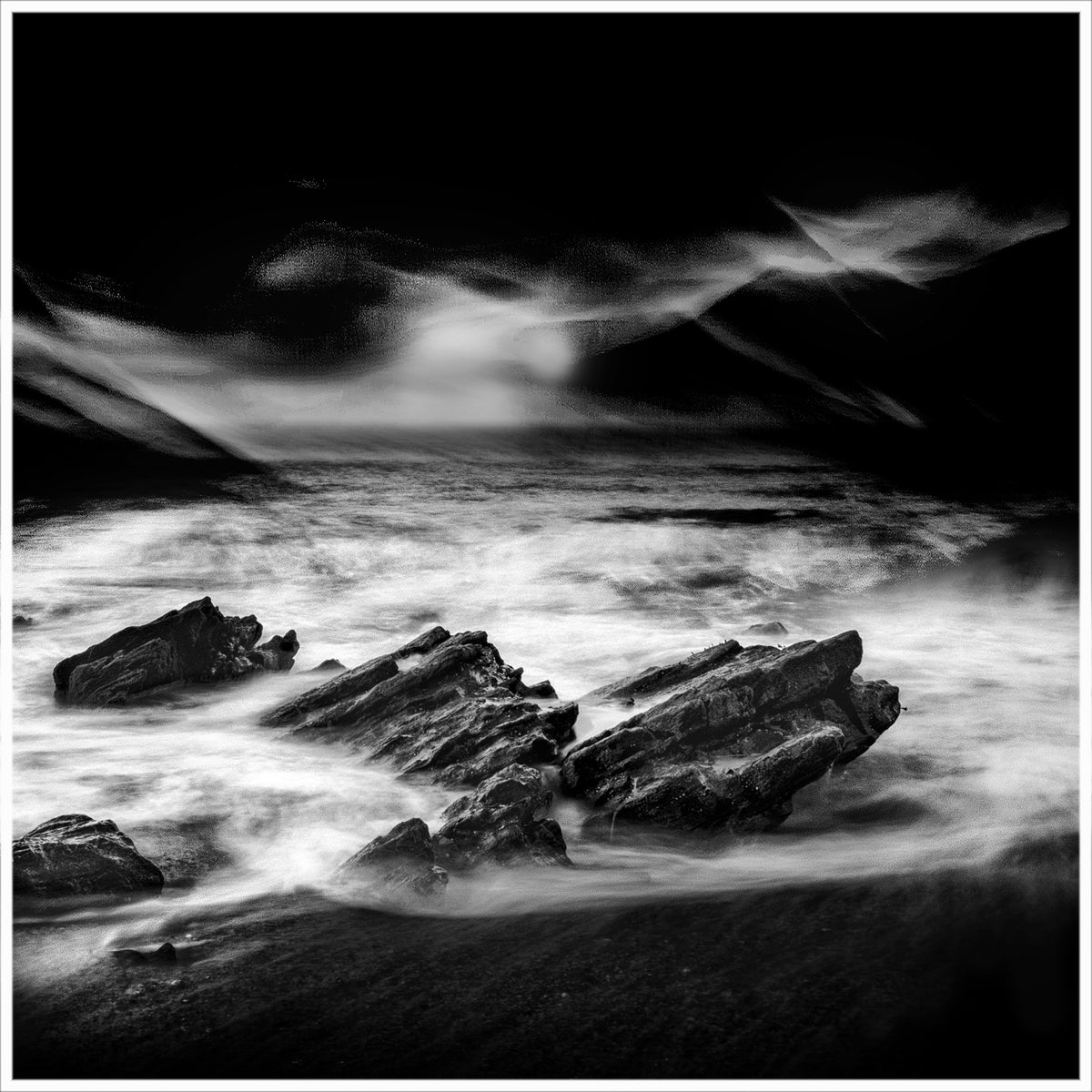 Night Surge — jagged dark rocks engulfed by swirling white water under a dramatically dark painterly sky, black and white fine art photography by Roy Fraser