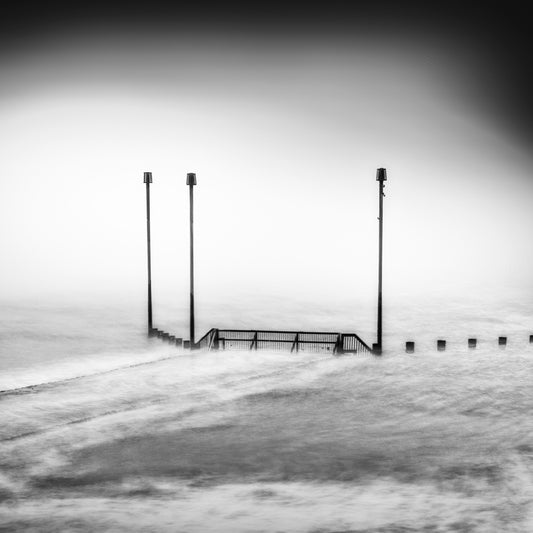 The Remaining, original black-and-white photograph of three upright posts and a railing in pale moving water.