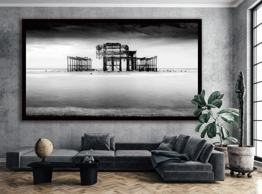 Panoramic black-and-white Brighton West Pier artwork in a black frame above a grey sofa.